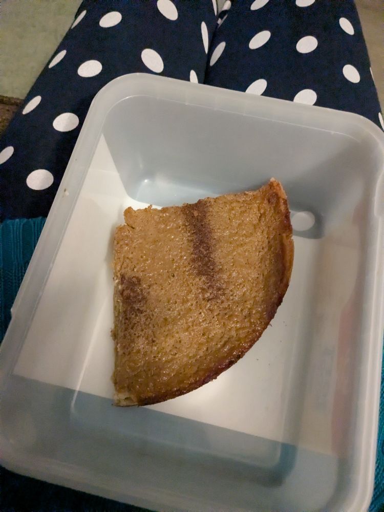 A large slice of pumpkin pie in an ice cream container. 