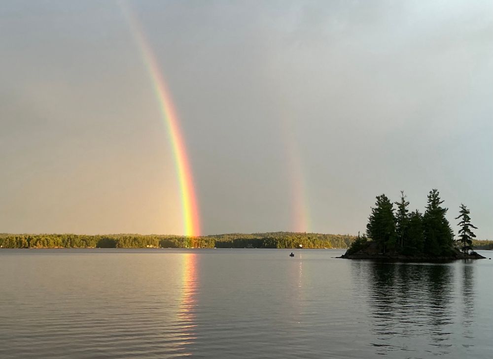 Double arc rainbow over a typical Georgian bay Canadian Shield lake and pine tree island 