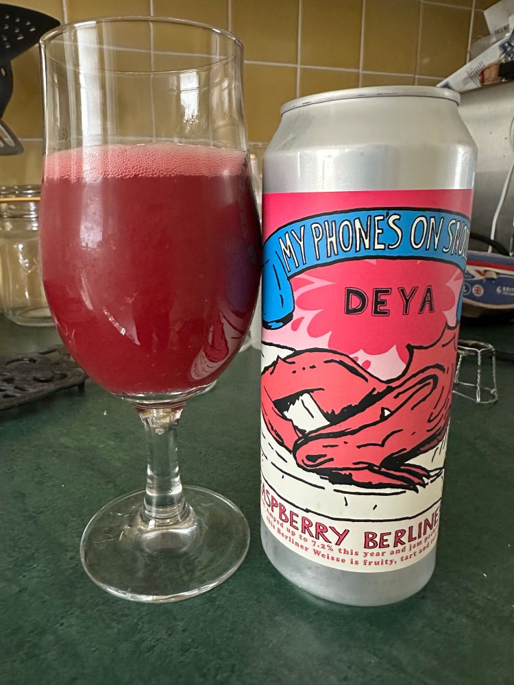 Schooner of deep raspberry coloured beer next to the can which pictures a sleeping dragon dreaming of raspberries.