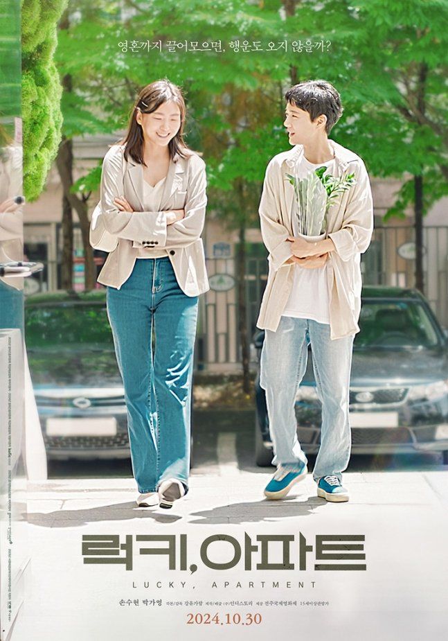 A poster of the 2024 South Korean film "Lucky, Apartment", showing two Korean women walking on the street, smiling. One short hair, one long hair. The woman with hort hair is holding a plant in her arm.