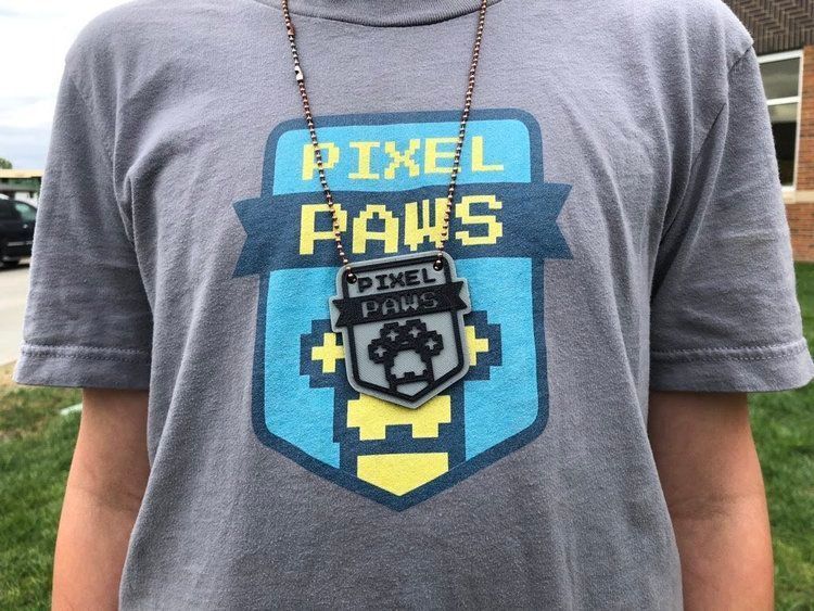 Student wearing a T-shirt and a 3D-printed necklace with the Pixel Paws logo