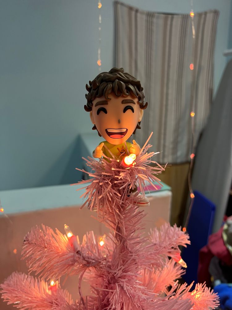 A close up of a Kurtis Conner Youtooz figure on the top of a pink faux christmas tree
