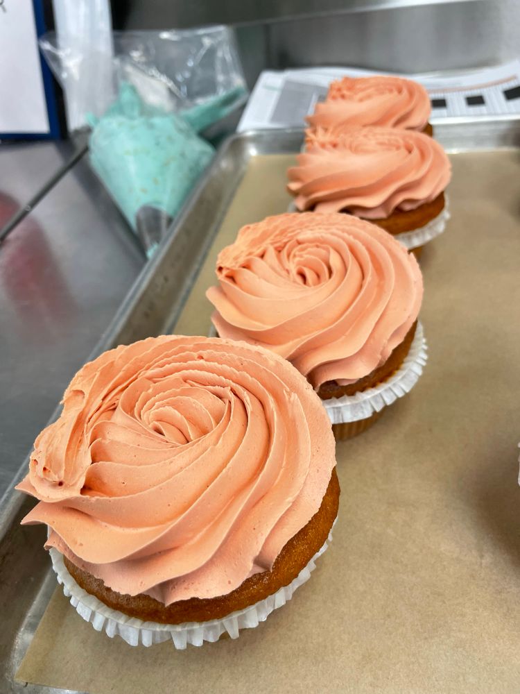 Peach colored frosting piped like a rose on a cupcake.