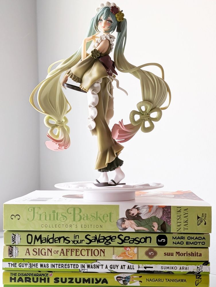A light green stack of manga, with a Matcha Miku pop up parade figure on top of it. 