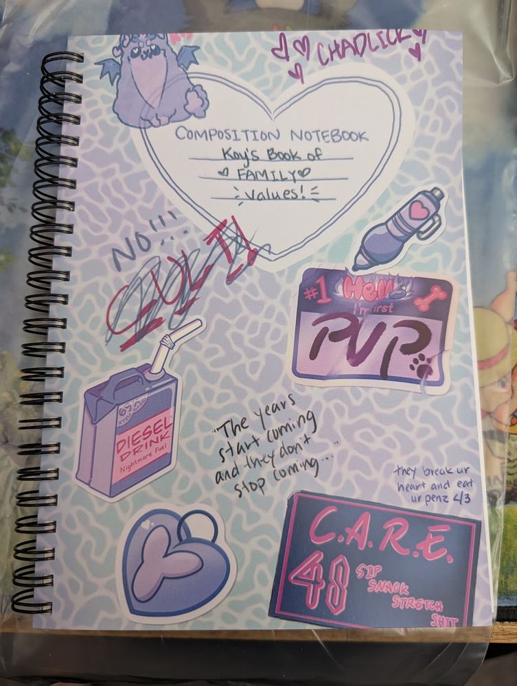 A spiral-bound notebook, with a hand drawn cover made to look like a composition notebook. It has several scribbles, and pictures drawn to look like stickers.