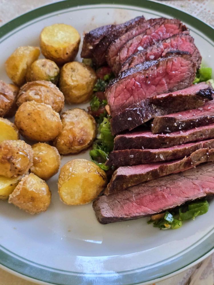 Australisches Wagyu Steak, medium rare, auf einem Bett aus Lauch, Kräutern und Tomaten mit gesalzenen frittierten Kartoffeln aus eigenen Anbau