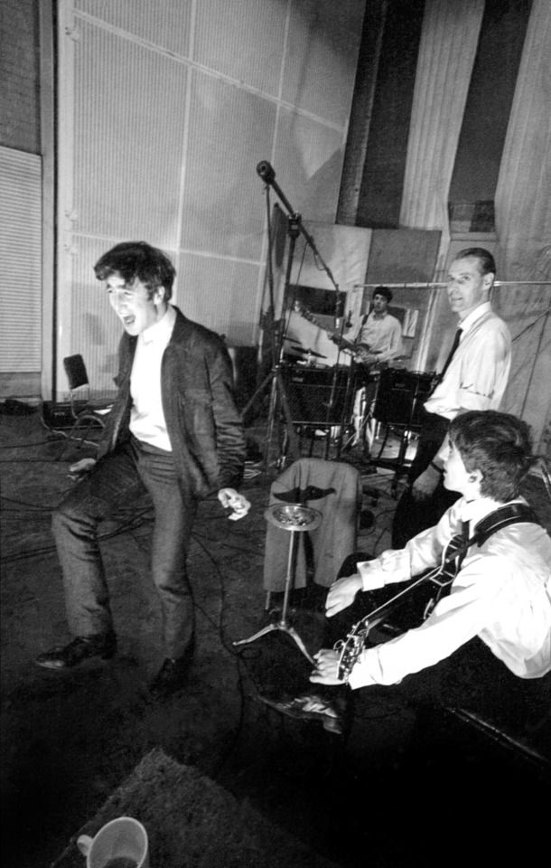 Black and white photo of John Lennon, George Harrison, George Martin and Paul McCartney in the studio. Taken by Norman Parkinson. George, George and Paul watch John as he screams