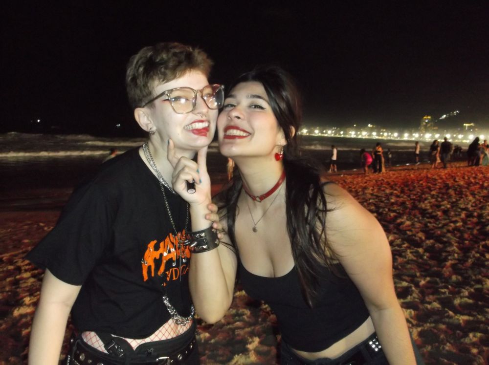 minha namorada, sorrindo, segura o meu rosto virado para a câmera mostrando que sujou a minha boca de batom vermelho