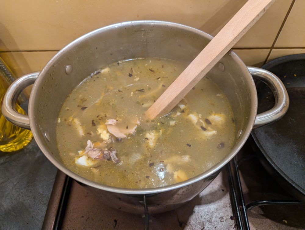 Photo of a sorrel soup in a pot with a big wooden spoon sticking out of it.