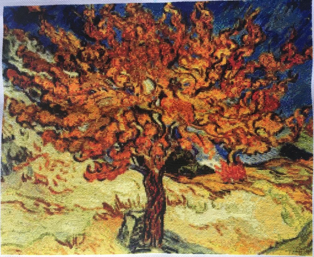 Cross stitch rendering of Van Gogh's Mulberry Tree painting. The tree's foliage appears to be writhing like fire, in shades of red and orange, set against a dark blue sky and yellow ground.