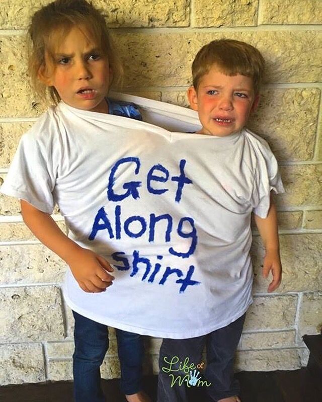 Two children, one a bit larger than the other, are both at the same time wearing an oversized T-shirt that says "Get Along Shirt." The children look distressed and are not "getting along."
