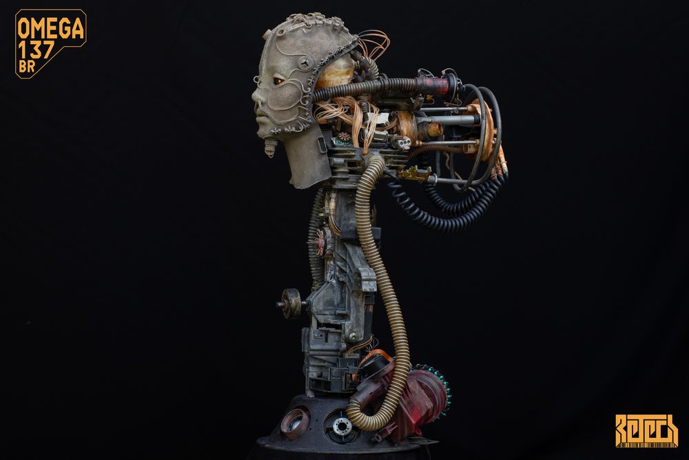 A sculpture of a mostly human face with biomechanical head and support structure. 