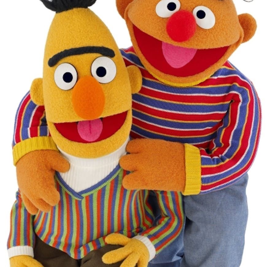 A grinning Ernie hugs a grinning Bert.