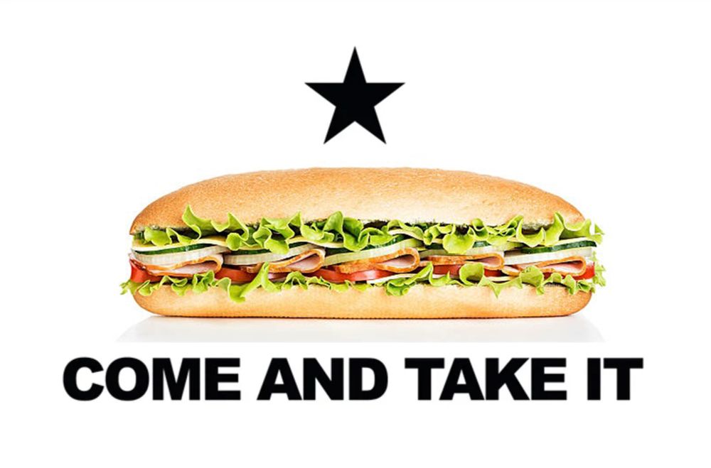 Might be a Gonzalez flag variant with an image of a sub sandwich instead of a cannon underneath the black star and above the words “COME AND TAKE IT” on a white background.