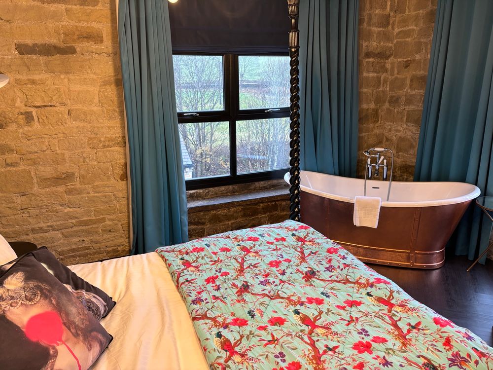 A picture of a bathtub next to a bed in a hotel room. 