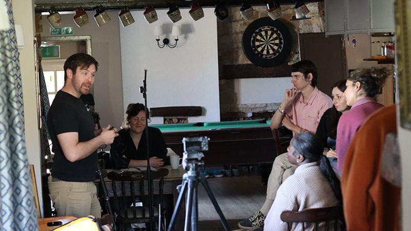 trainees looking at man demonstrating camera interview set up
