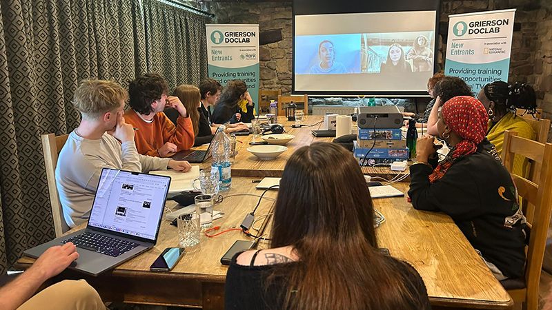trainees sat around table looking at projector screen

