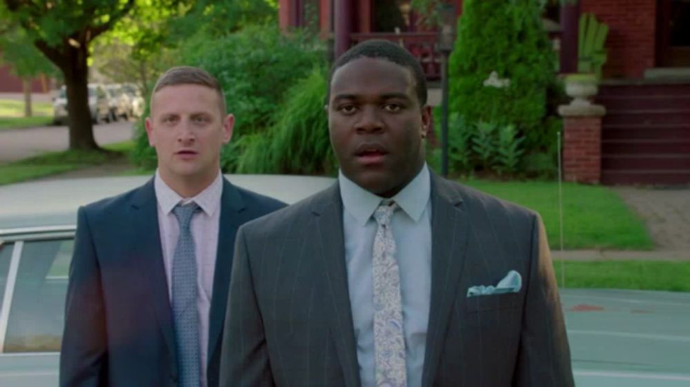 a man in a suit and tie stands next to another man in a suit