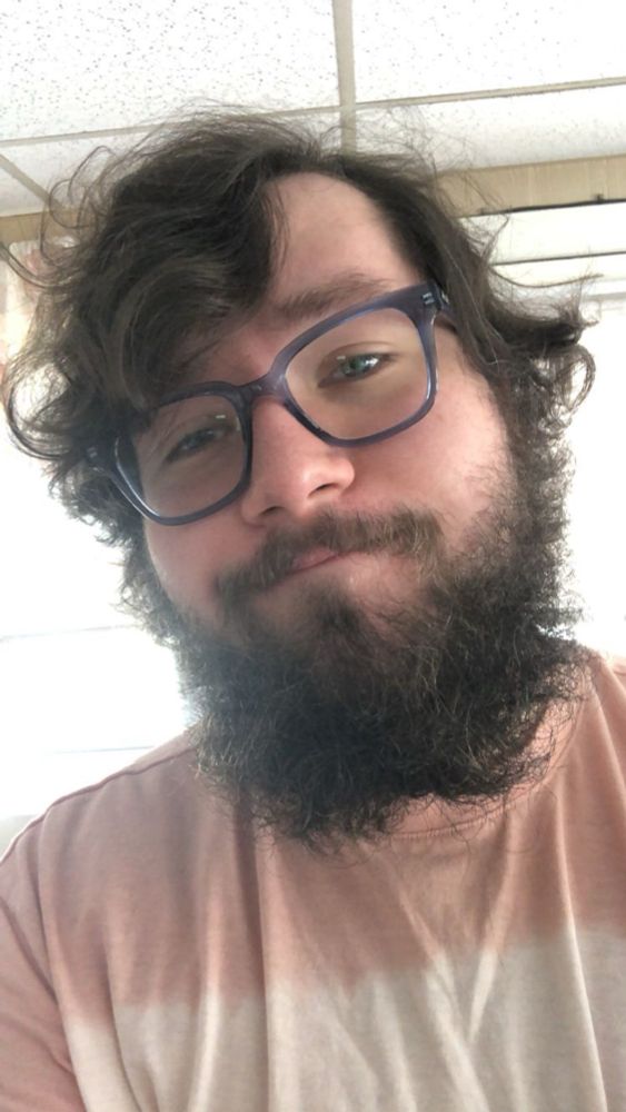 Me with a pink shirt, extremely messy and somewhat long hair, as well a messy unkempt beard