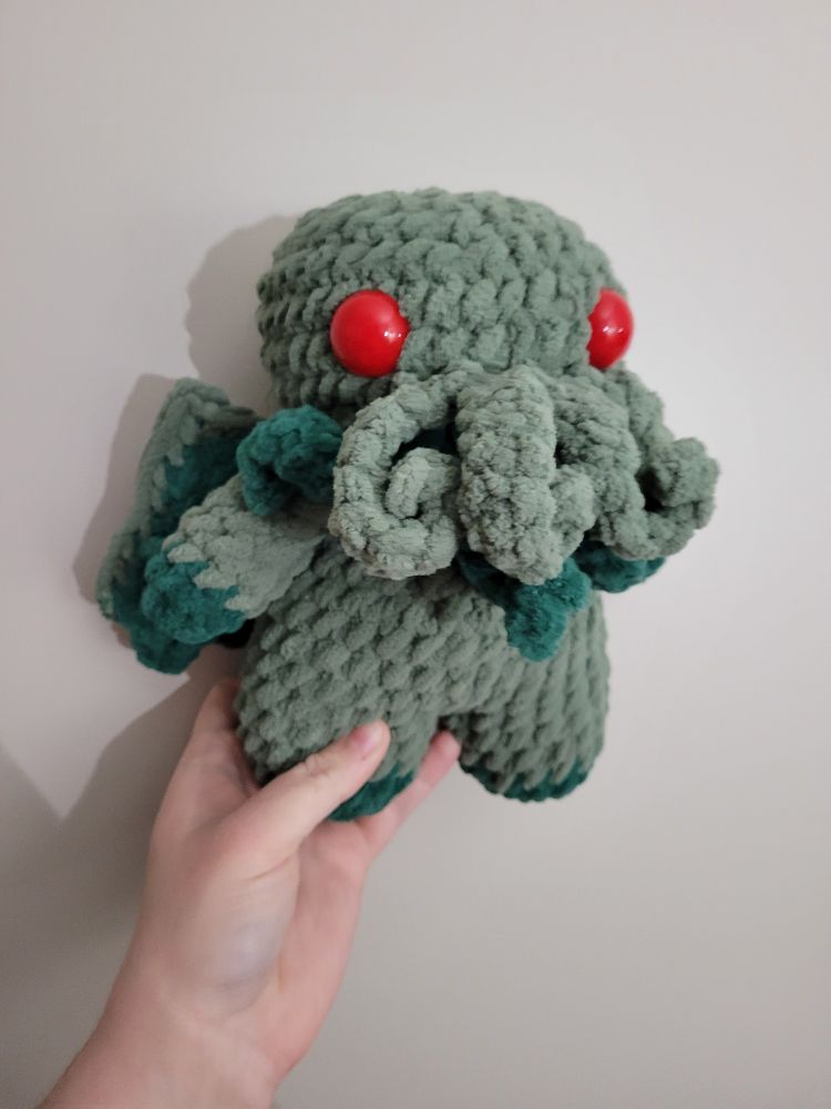 Sage green cthulhu with red eyes and dark green accents. Short stubby style looks cuddly. 