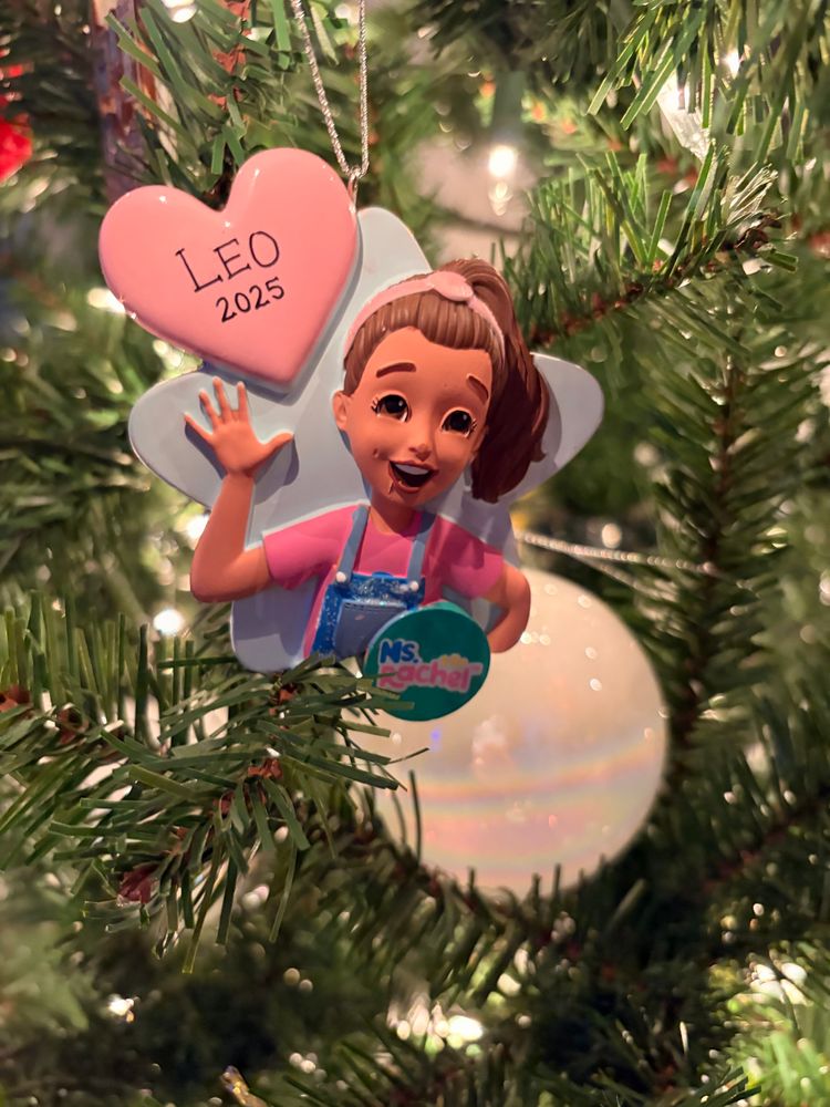 A photo of a Ms. Rachel ornament with Leo 2025 written in a heart. It’s a little creepy looking tbh and Rachel is giving biracial baddie