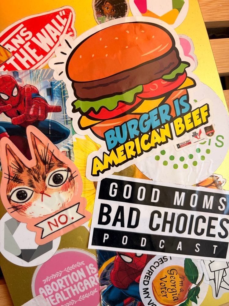 A photo of an iPad. The following stickers are visible: good mom’s bad choices. Abortion is healthcare. A cat with the word no under it. I secured my photo Georgia voter. Spider-Man. Burger is American beef. 