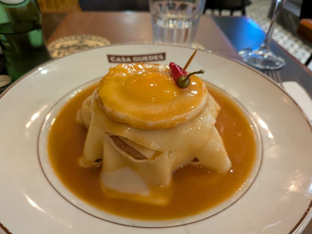 A Francesinha dish from Porto - a sandwich with ham, roast pork and bacon topped with cheese and a fried egg, served in slightly spicy tomato beer sauce 