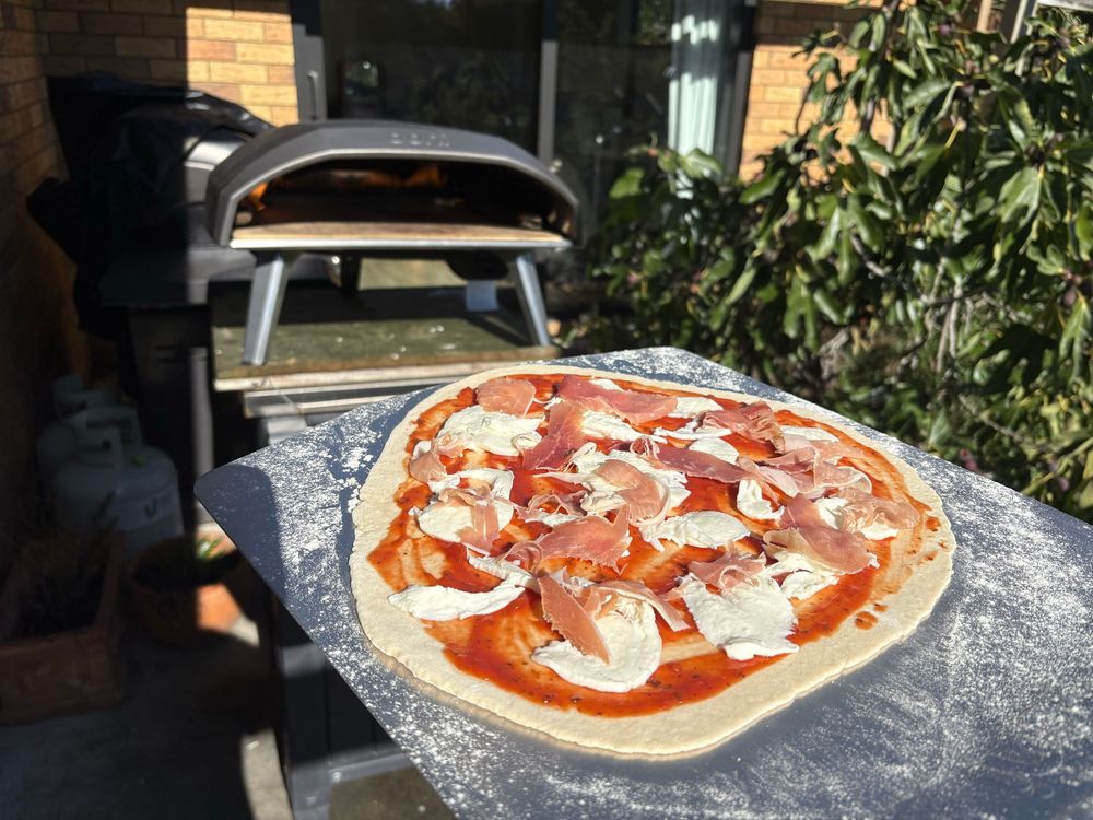 Pizza with buffalo mozzarella and prosciutto ham making its way to the Ooni pizza oven.