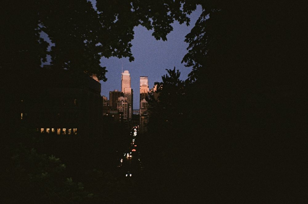 A photo of an evening Montreal cityscape glimpsed through a gap in some trees.