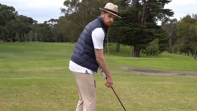 a man wearing a hat and vest is holding a golf club