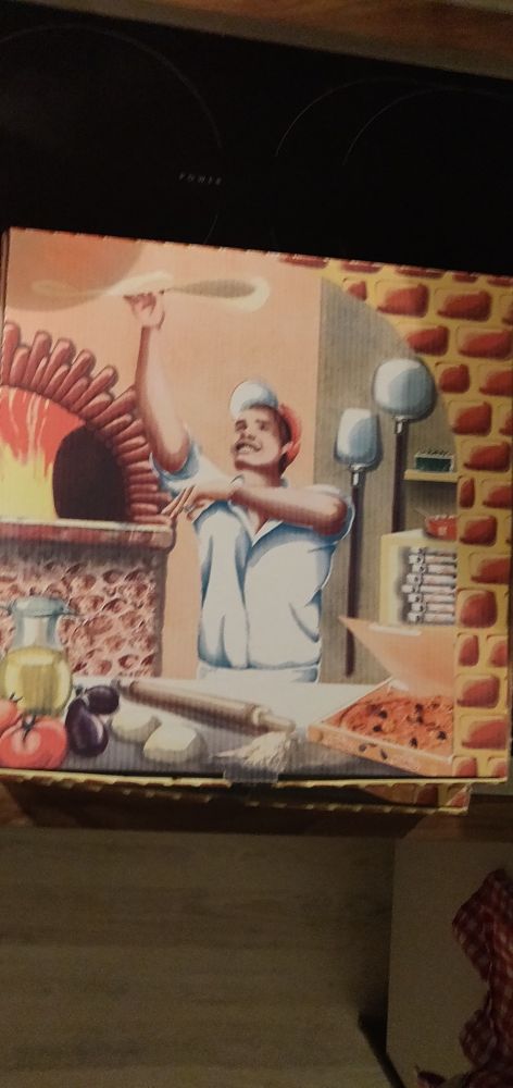 Junger Pizzabäcker der einen Teig in die Luft wirft