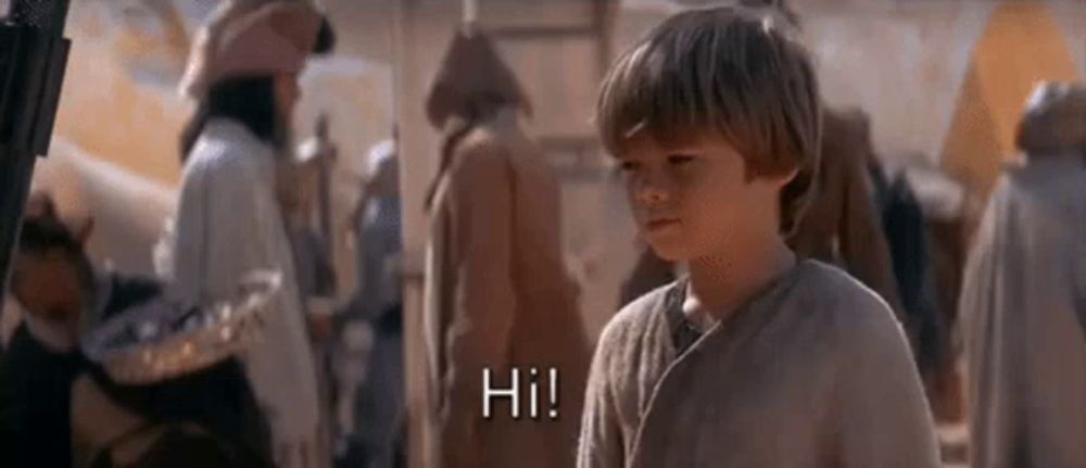 a young boy is standing in front of a group of people and saying `` hi '' .