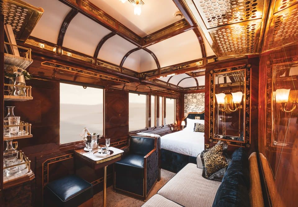 Photo of the incredibly luxurious bedroom and a living room in a luxury grand cabin suite aboard the modern Orient Express.
