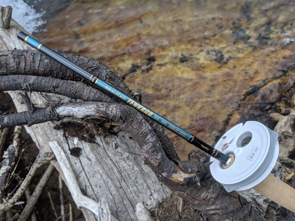 Tenkara fishing rod and line spool resting on a fallen tree