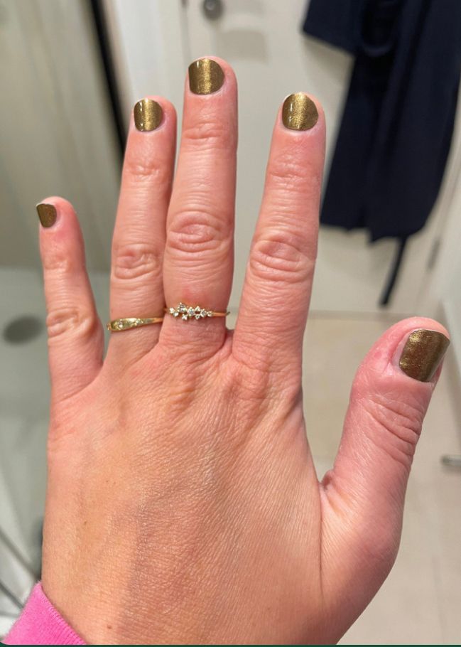 Left hand held to show gold nail polish on 5 fingers, similar to the gold colour worn by Taylor Swift in recent months 