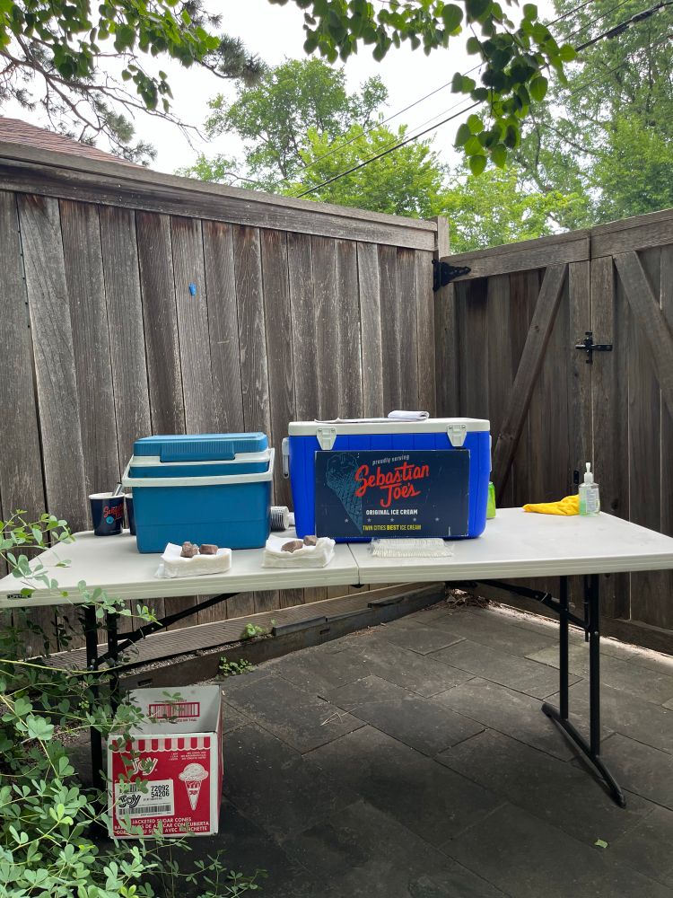 A folding table with two coolers of ice cream