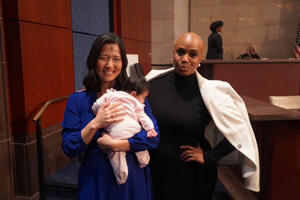 Photo of Boston Mayor Michelle Wu and Congresswoman Ayanna Pressley at a House Oversight Committee hearing. Mayor Wu is holding her infant daughter Mira.