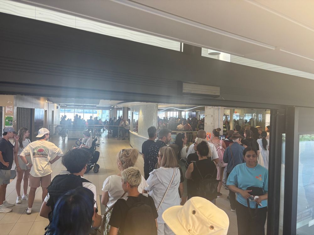 Picture of the interior of the Dartmouth ferry terminal with a long line of annoyed people waiting for the ferry. 