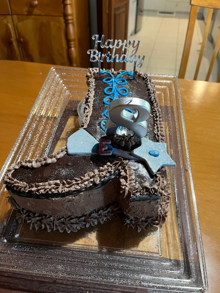 Cowgirl boot shaped cake with spur and decoration and with a candle shaped as the number 8