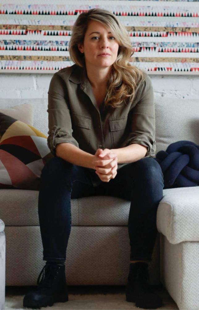 Mélanie Joly, Minister of Foreign Affairs of Canada, seated on a couch dressed casually wearing blue jeans and hiking boots.