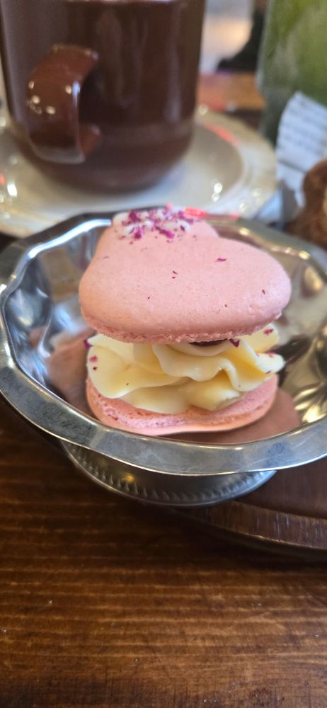 A lychee and raspberry macaron, where the shell is shaped like a heart and the inside is a luxurious swirl of cream.