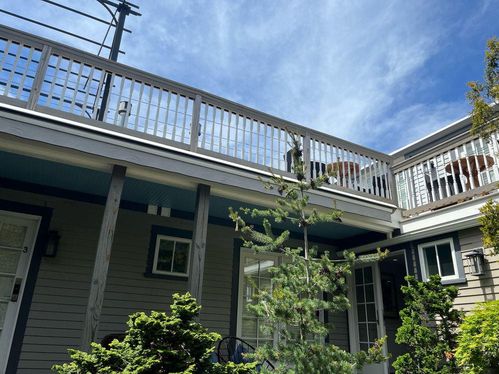 Looking up at the mostly-blue sky with traces of clouds in a courtyard of a guest house.
