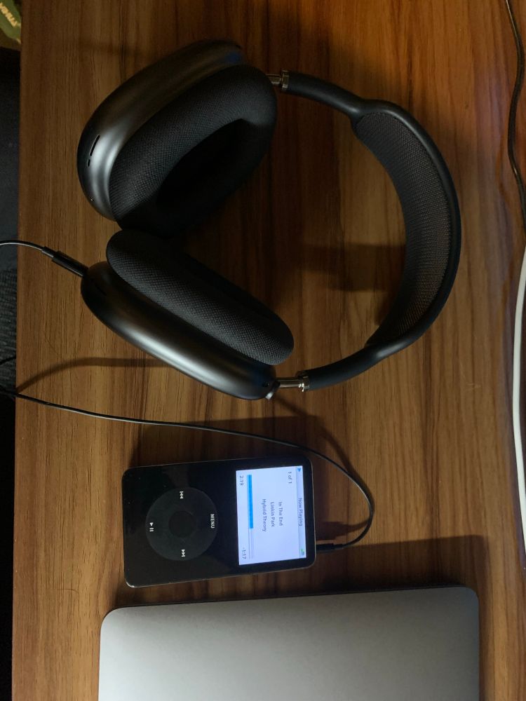 A black iPod classic, 5th gen plugged into AirPods Max 