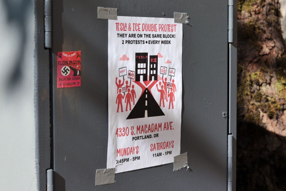 A close-up image of the side of a utility box. A flyer is taped to the utility box. The flyer reads: “TESLA & ICE DOUBLE PROTEST | THEY ARE ON THE SAME BLOCK! | 2 PROTESTS EVERY WEEK | 4330 S. MACADAM AVE. | PORTLAND, OR | MONDAYS  3:45PM - 5PM | SATURDAYS  11AM - 1PM”. 

The flyer depicts protestors with picket signs standing on both sides of a road. The road on the flyer leads toward two buildings, one labeled, “TESLA”, and the other labeled, “ICE”. A sticker has been placed to the left of the flyer. The sticker depicts a swastika and an image of Elon Musk performing a Nazi salute. The text on the sticker reads: “ELON MUSK | DRIVE THE FUTURE OF FASCISM”. 

At 3:45pm on May 5th, 2025, protestors gathered outside the Portland Tesla dealership on Macadam Ave to protest the fascist regime of Donald Trump and Elon Musk.
