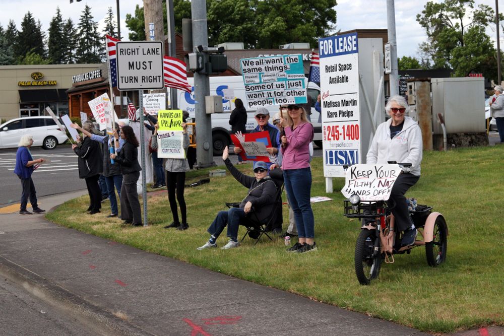 Demonstrators carrying picket signs line one corner of the intersection. Several smile and wave towards passing traffic.

At 4pm on May 19th, 2025, demonstrators in Vancouver, WA gathered at the intersection of Mill Plain and Chaklov to protest the destruction of essential social services by US President Donald Trump's fascist regime.