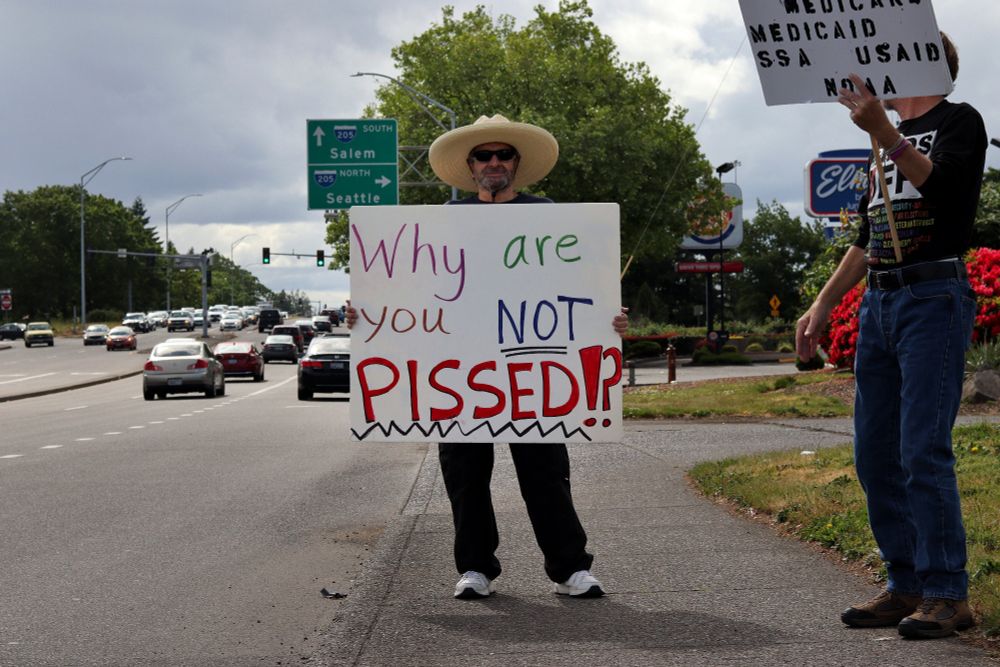 A demonstrator wearing a sombrero while standing beside the road holds up a sign towards the viewer which reads, "Why are you NOT PISSED!?"

At 4pm on May 19th, 2025, demonstrators in Vancouver, WA gathered at the intersection of Mill Plain and Chaklov to protest the destruction of essential social services by US President Donald Trump's fascist regime.