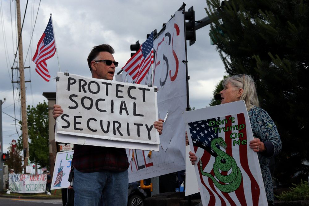 Two protestors hold up picket signs while speaking to each other. The protestor on the left of the image carries a sign which reads, "PROTEST SOCIAL SECURITY," while the protestor on the right of the image carries a sign which reads, "Don't Trump on Me" and depicts and image of a coiled snake over a US Flag.

At 4pm on May 19th, 2025, demonstrators in Vancouver, WA gathered at the intersection of Mill Plain and Chaklov to protest the destruction of essential social services by US President Donald Trump's fascist regime.