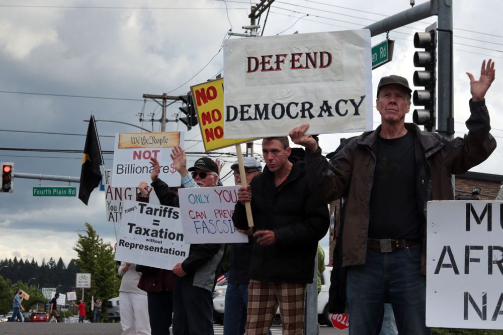 Protestors line the side of the road, holding picket signs toward the viewer. From right to left, the visible signs read: “WE THE PEOPLE | NOT BILLIONAIRE$”, “Trump’s Tariffs = Taxation without Representation”, “ONLY YOU CAN PREVENT FASCISTS”, and “DEFEND DEMOCRACY”. 

At 5:00pm on May 7th, 2025, protestors gathered at the intersection of NE Fourth Plain Blvd and NE Andresen Rd outside the Vancouver, WA, Tesla dealership to protest the fascist regime of President Donald Trump and unelected billionaire Elon Musk.
