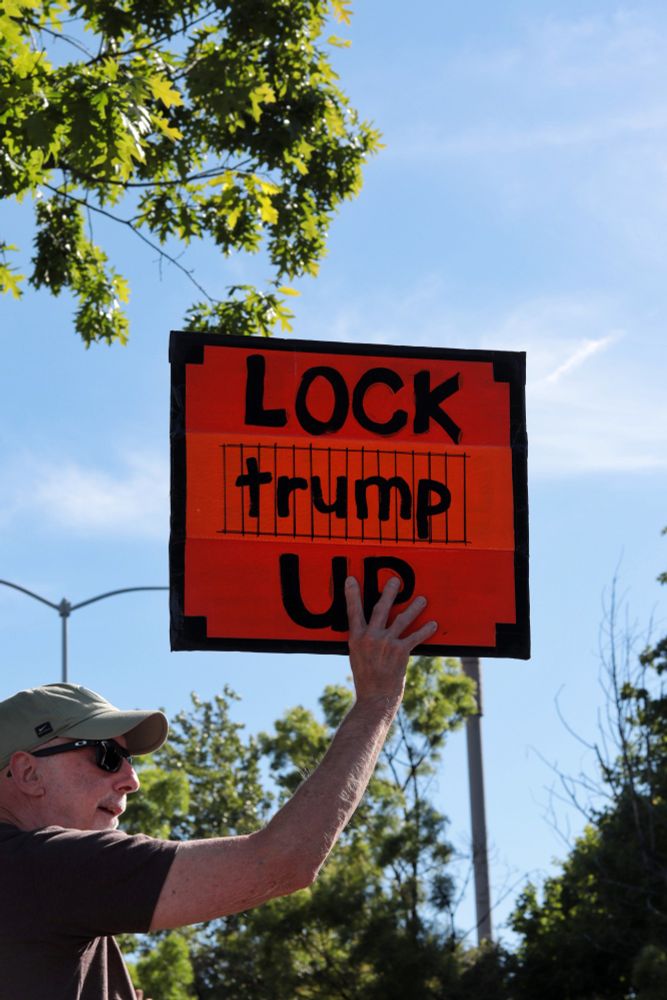A protestor holds up an orange sign which reads "LOCK trump UP" and depicts the word "trump" behind bars.

At 3:45pm on May 5th, 2025, protestors gathered outside the Portland Tesla dealership on Macadam Ave to protest the fascist regime of Donald Trump and Elon Musk.
