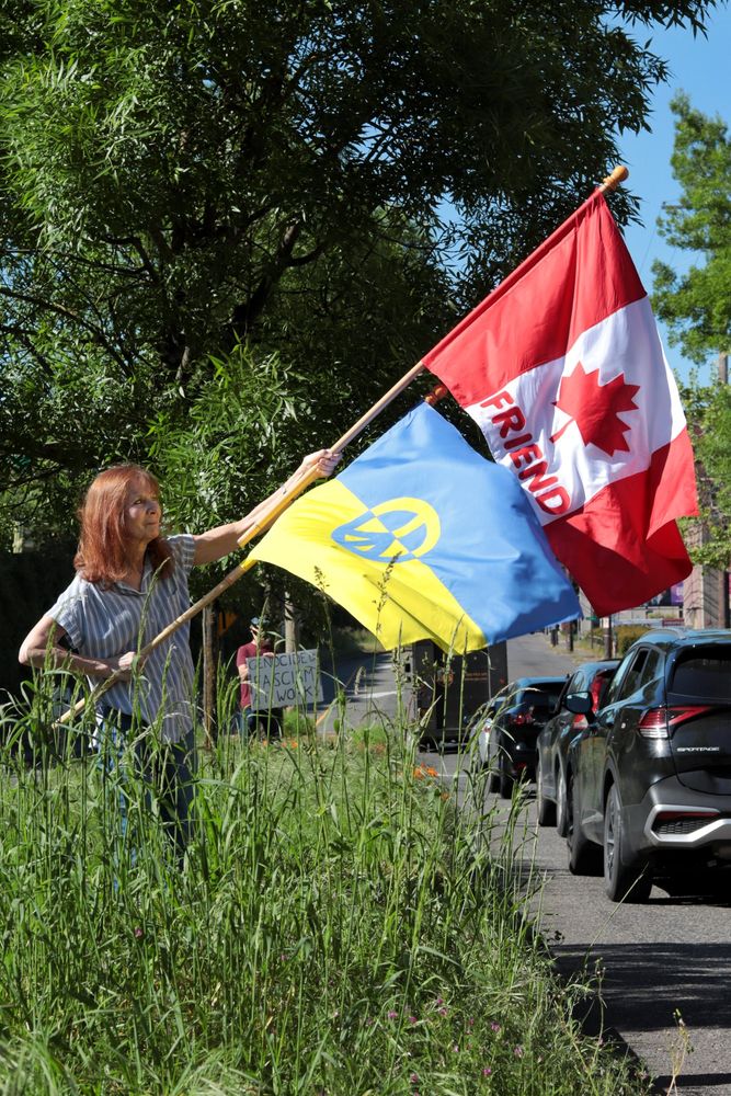 A protestor holds up two flags. One flag is the flag of Canada with the word "FRIEND" printed under the maple leaf. The other flag is the flag of Ukraine with a peace sign superimposed over the standard.

At 3:45pm on May 5th, 2025, protestors gathered outside the Portland Tesla dealership on Macadam Ave to protest the fascist regime of Donald Trump and Elon Musk.

